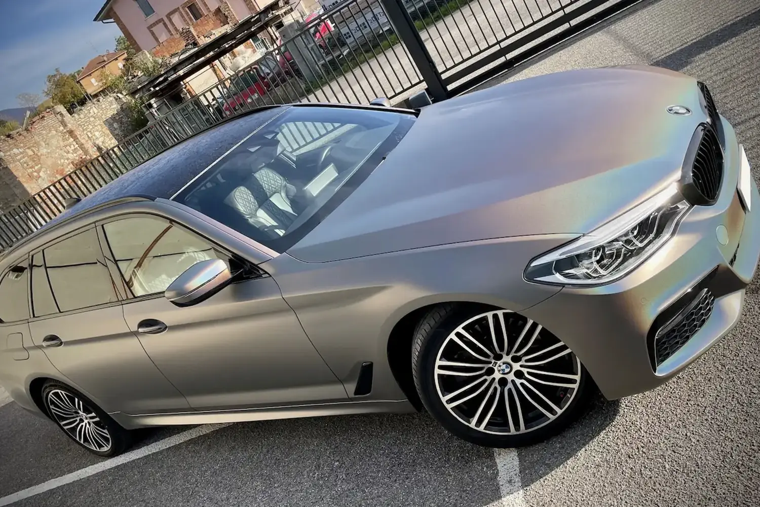 BMW Serie 5 Touring rivestita con pellicola cangiante effetto olografico in tonalità bronzo e viola, con cerchi in lega multirazza e interni chiari.